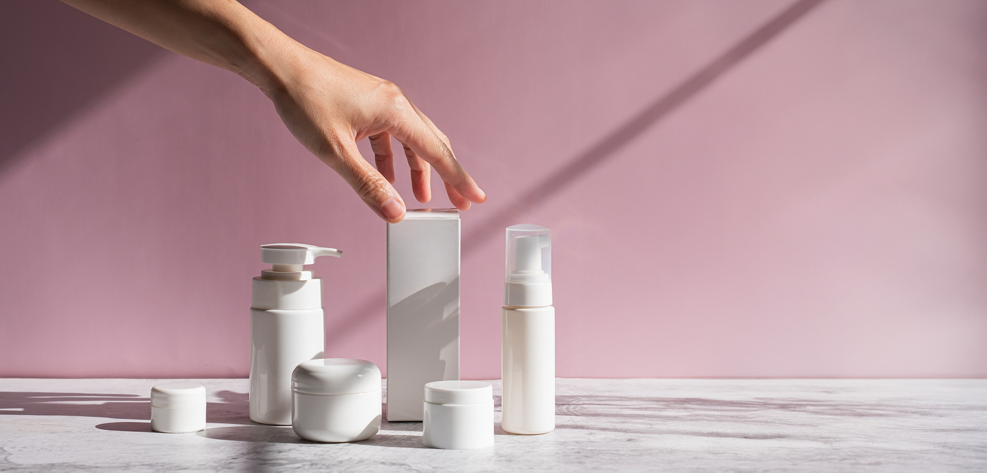 Hand is touching skincare set for cosmetic and beauty concept.